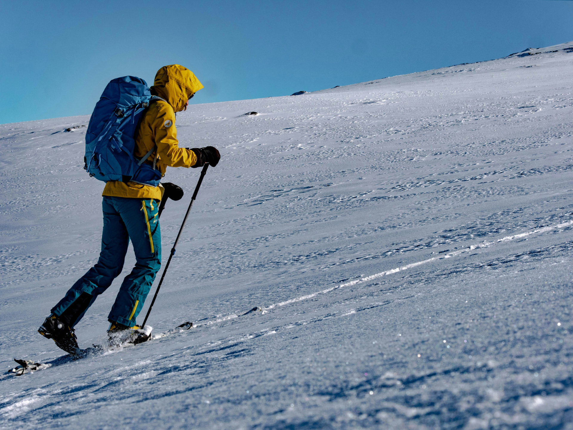 Skiløper på vei opp snødekt fjellside